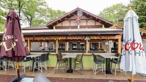 An outdoor seating area with tables and chairs, a covered patio, and a building with a pitched roof and wooden beams. - Beautiful, Cozy, All-Seasons Mountain/Lake Townhome (Lake Harmony)