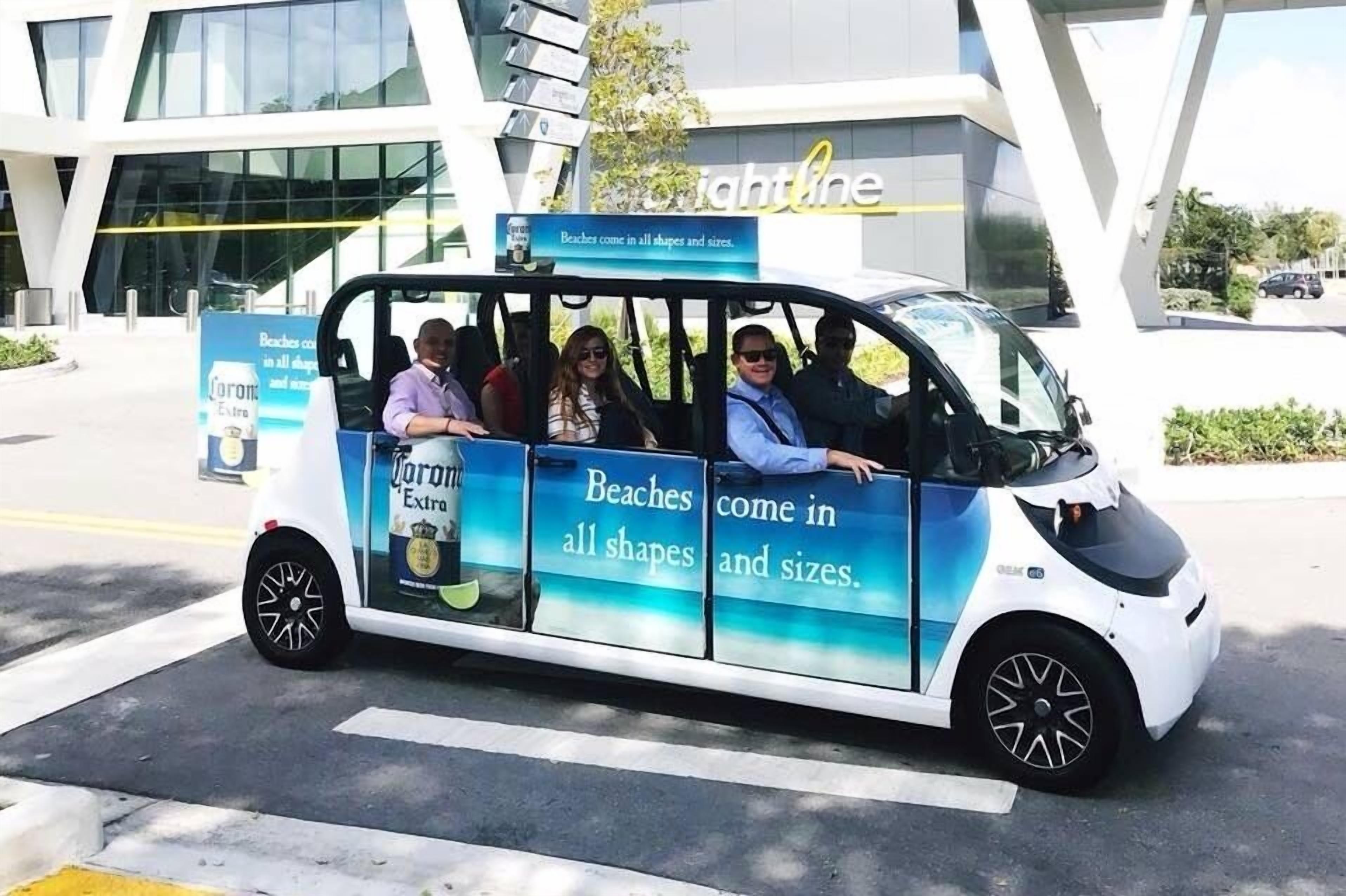 A small electric vehicle with advertisements for Corona beer and a slogan about beaches.