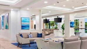 Een moderne hotellobby met een zithoek, kunstwerken aan de muren en uitzicht op het groen.