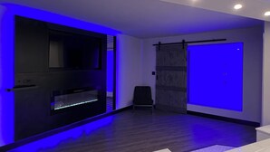 Uma sala de estar moderna com televisão de tela plana, área de estar e uma janela grande com vista.