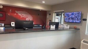 Uma receção com design moderno, incluindo um ecrã digital, um computador e uma câmara de segurança.