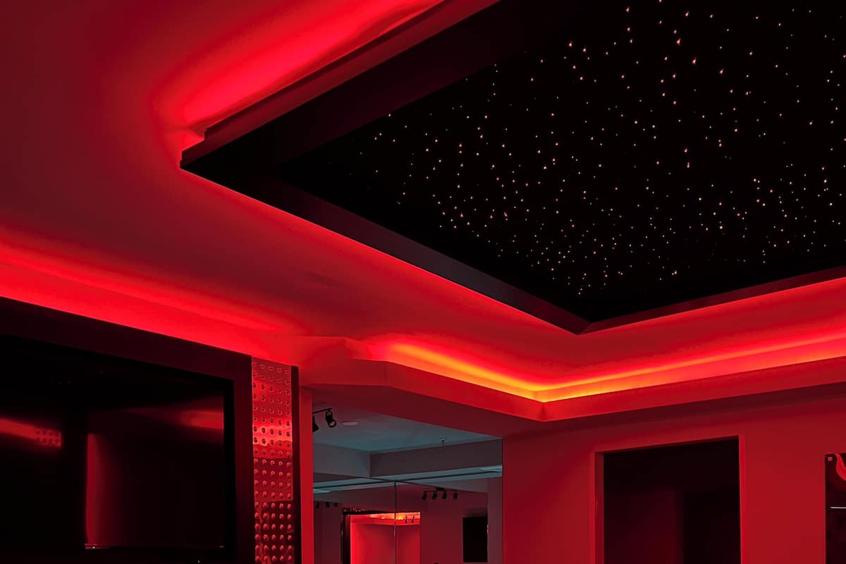 A modern bedroom with a large bed, a built-in TV, and a unique ceiling design.