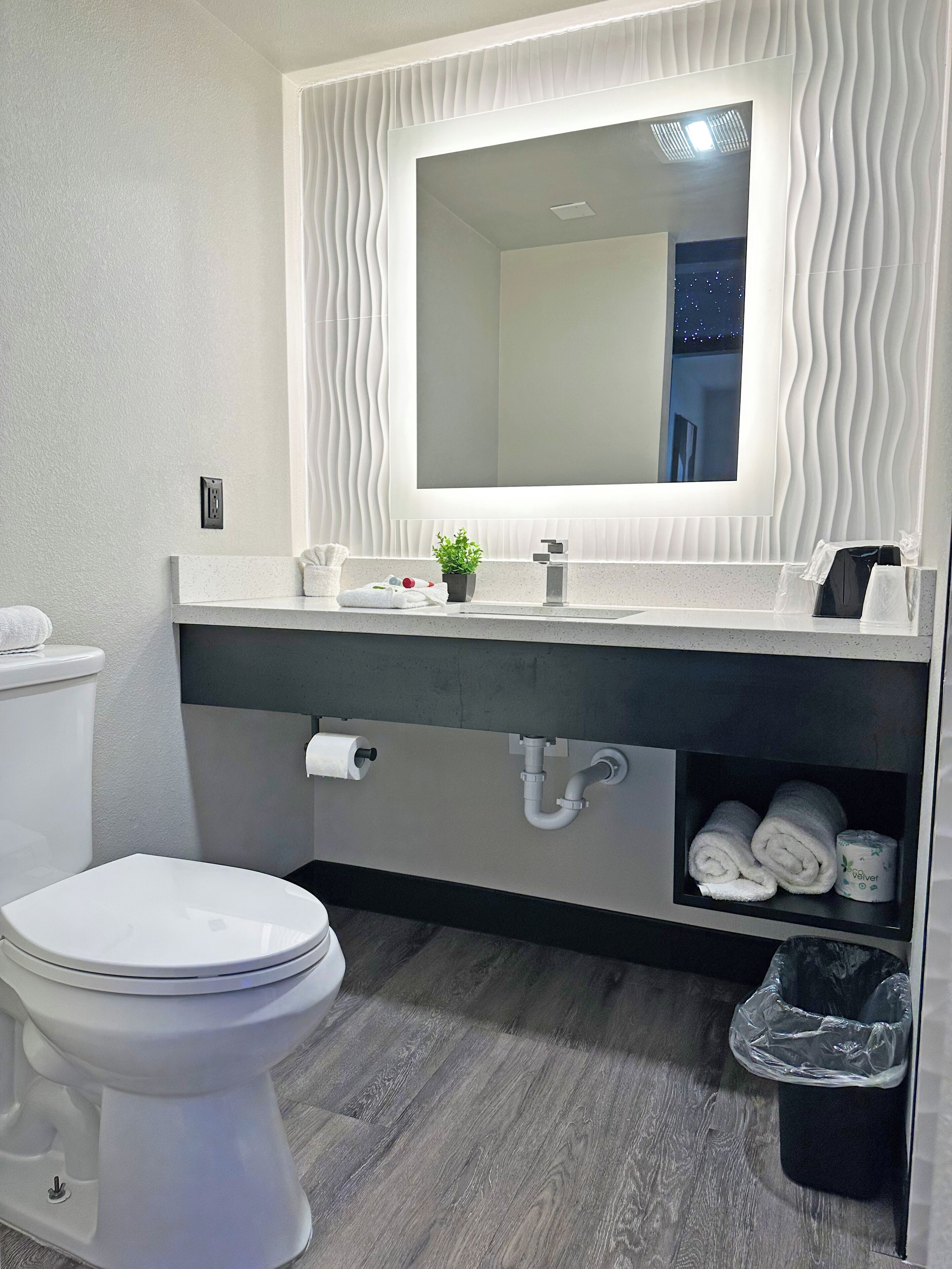 A modern bathroom with a white toilet, a vanity with a mirror, and a towel rack.