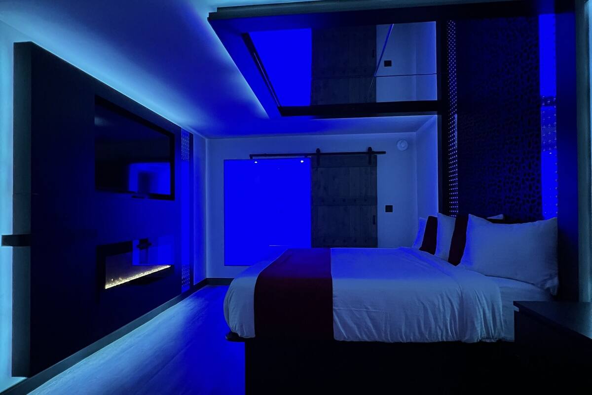 A modern bedroom with a bed, a desk, and a built-in wardrobe.