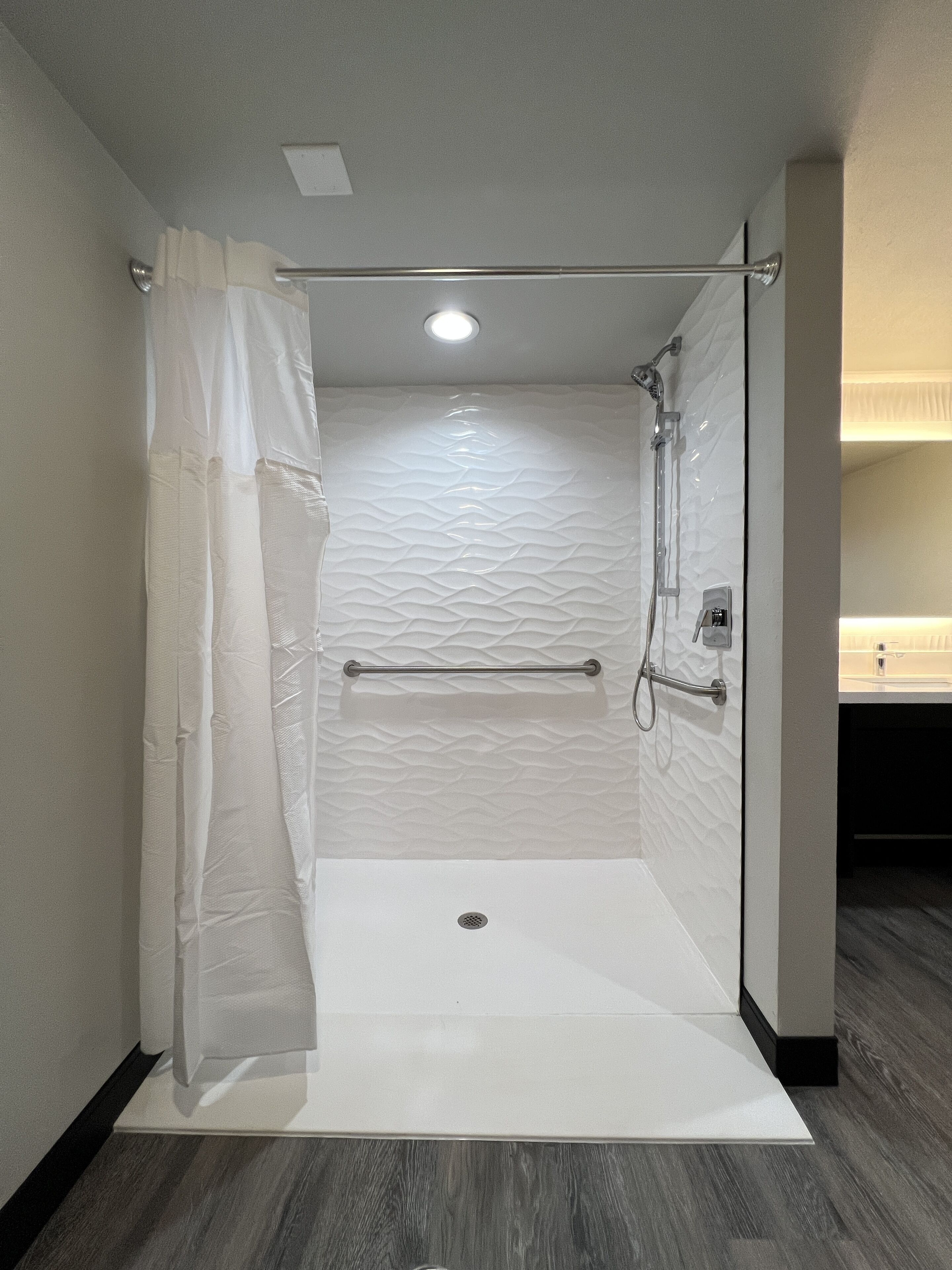 A modern shower area with a glass door, a towel bar, and a showerhead.