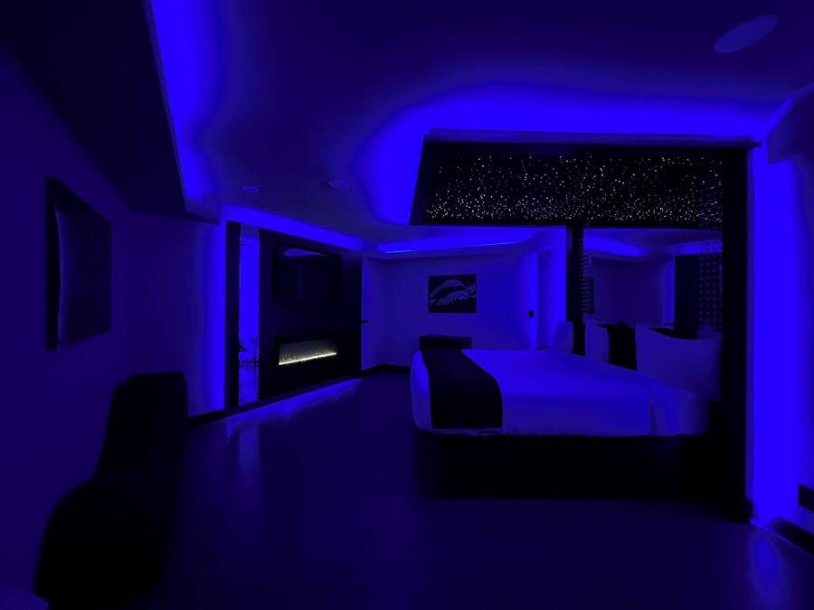 A modern bedroom with a bed, a desk, and a starry ceiling design.