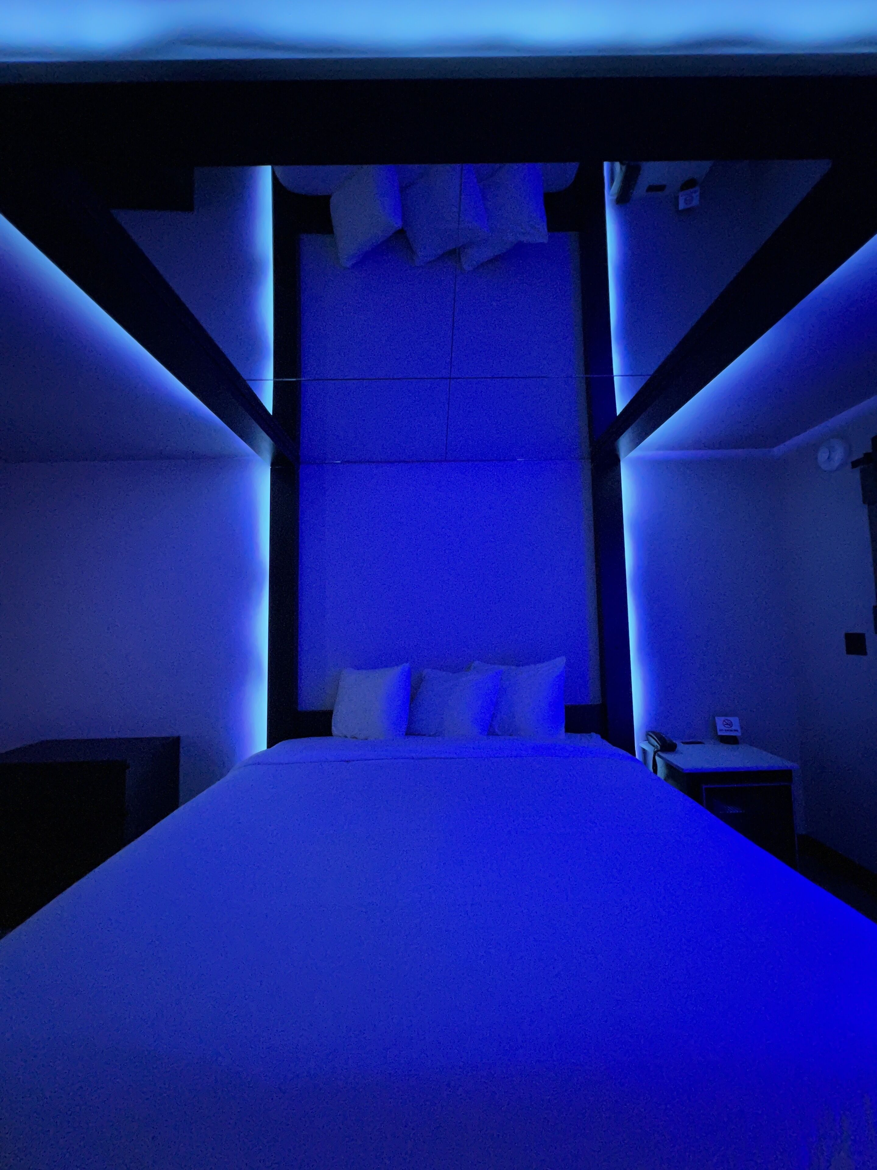Een kamer met een bed, een nachtkastje en een klok aan de muur.