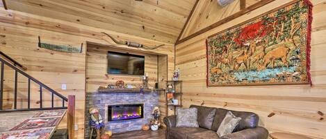 Un acogedor interior de cabaña de madera con chimenea, sofá de cuero y un tapiz grande.