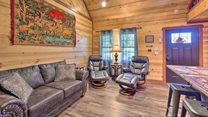 A cozy cabin interior with a wooden ceiling, a large tapestry, leather furniture, and a dining area. - Secluded & Peaceful: 'Tree Top Cabin' w/ Loft (Hot Springs)