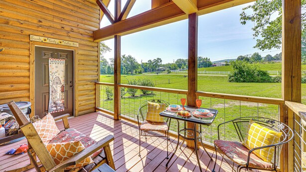 A wooden cabin with a porch featuring a table with plates and glasses, a bench, and a chair with cushions. - Secluded & Peaceful: 'Tree Top Cabin' w/ Loft (Hot Springs)