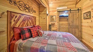 A wooden cabin interior with a bed, a mirror, and a door. - Secluded & Peaceful: 'Tree Top Cabin' w/ Loft (Hot Springs)