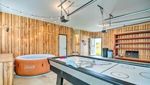 A pool table with a wooden backdrop and string lights, a hot tub, and a bookshelf. - Charming Lewisburg Home w/ Hot Tub & Games! (Lewisburg)