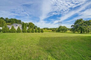 A grassy field with a house and trees in the background. - Charming Lewisburg Home w/ Hot Tub & Games! (Lewisburg)