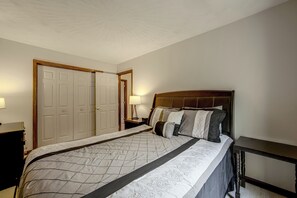 A bedroom with a large bed, a nightstand, a dresser, and a door. - Charming Lewisburg Home w/ Hot Tub & Games! (Lewisburg)