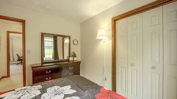 Un dormitorio con cama, cómoda, espejo, reloj de pared y una puerta.