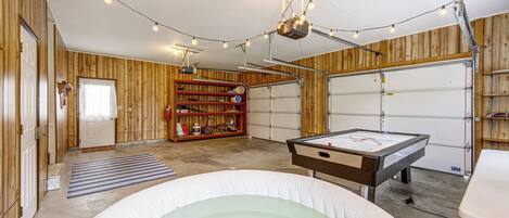 Une salle de loisirs équipée d’une table de billard, d’un jacuzzi et d’un mur en bois avec des étagères.