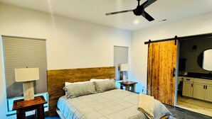 Et moderne soveværelse med seng, natbord, ventilator i loftet og en skydedør i lade-stil.