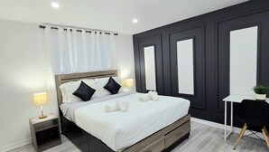 A modern bedroom with a bed, bedside tables, a desk, and a potted plant. - Ultimate Retreat: 98" Cinema + Arcade Game Room + BBQ + Airport (Brampton)