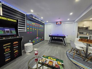 A room with a foosball table, a foosball table with a TV, and a foosball table with a game on it.