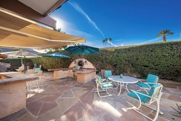 Relax in a serene outdoor space with a round table, chairs, and barbecue station.