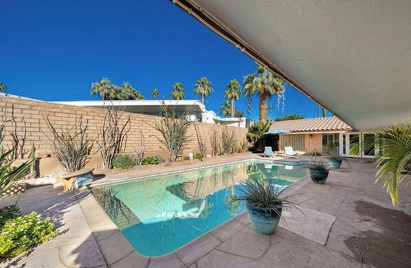 A backyard with a swimming pool, palm trees, and a brick wall. - Vintage 1959 mid century modern, close to tennis and festivals (Indian Wells)