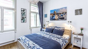 Una camera da letto con un letto grande, un comodino, una lampada a parete e una finestra con tende.