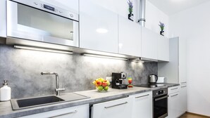Una cucina moderna con una cappa aspirante in acciaio inox, un forno integrato, una macchina da caffè e una ciotola di frutta sul piano di lavoro.