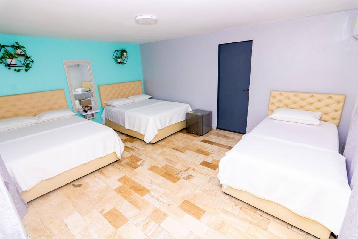 A hotel room with two beds, a wardrobe, a mirror, and a door.