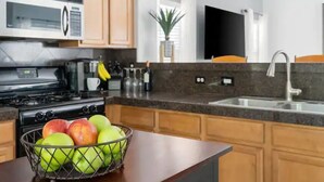 A kitchen with a microwave, stove, sink, and a fruit bowl on the counter. - Stylish Central Tucson Family-sized Home with Bikes to Ride (Tucson)