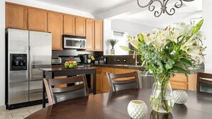 A modern kitchen with wooden cabinets, stainless steel appliances, and a dining table with chairs. - Stylish Central Tucson Family-sized Home with Bikes to Ride (Tucson)