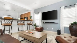 A modern living room with a sofa, a coffee table, and a TV mounted on the wall. - Stylish Central Tucson Family-sized Home with Bikes to Ride (Tucson)