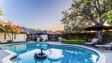 A backyard with a swimming pool, inflatable swan floats, and outdoor furniture.