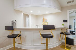 A bar area with three stools, a counter, and a wall-mounted sign.