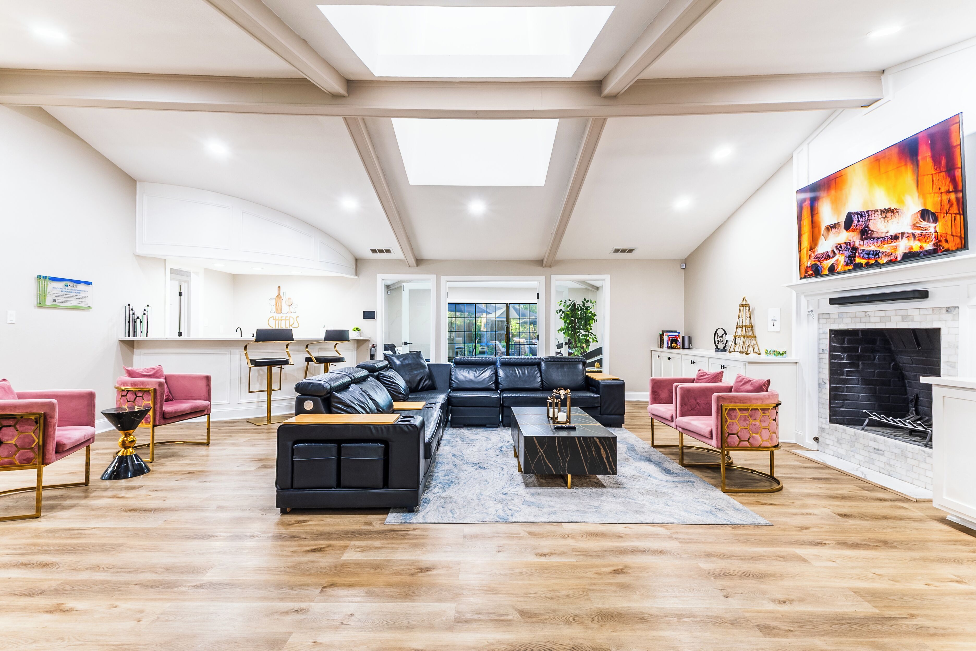A spacious living room with a black sectional sofa, a fireplace, and a large window.