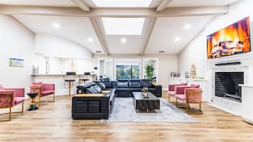 A spacious living room with a black sectional sofa, a fireplace, and a large window.