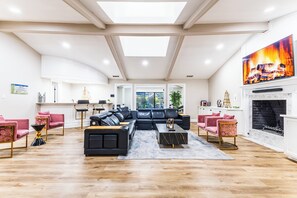 A spacious living room with a black sectional sofa, a fireplace, and a large window.