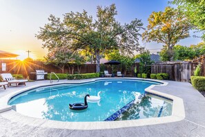 A swimming pool with a swan float, surrounded by a wooden fence, and a barbecue grill in the background. - ★4BR Dallas Family Estate | Heated Pool + Hot Tub | Sleeps 16 | Lake Highlands★ (Dallas)