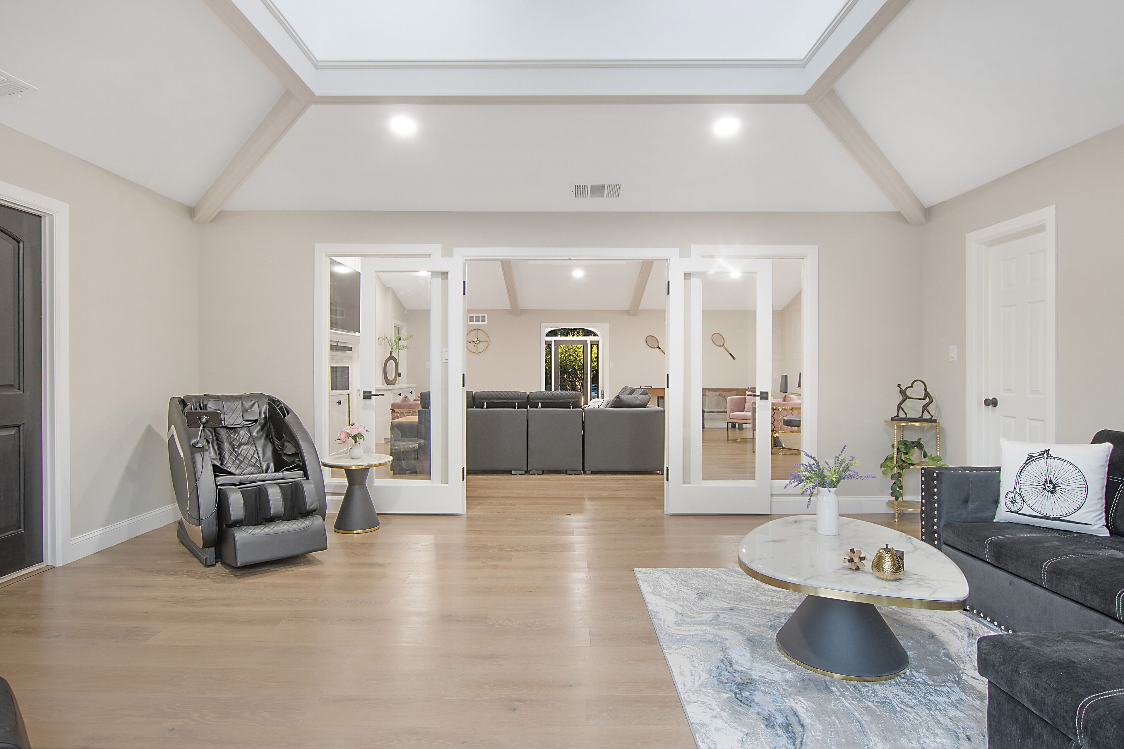 Un salón amplio con sillón de masaje, un sofá de color oscuro y una mesa de centro de mármol.