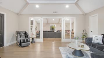 Un salón amplio con sillón de masaje, un sofá de color oscuro y una mesa de centro de mármol.