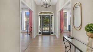 A hallway with a glass door leading to a patio, a black console table, and a potted plant. - ★4BR Dallas Family Estate | Heated Pool + Hot Tub | Sleeps 16 | Lake Highlands★ (Dallas)