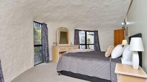 Un dormitorio con cama, mesita de noche, lámpara, cómoda y ventana con cortinas.