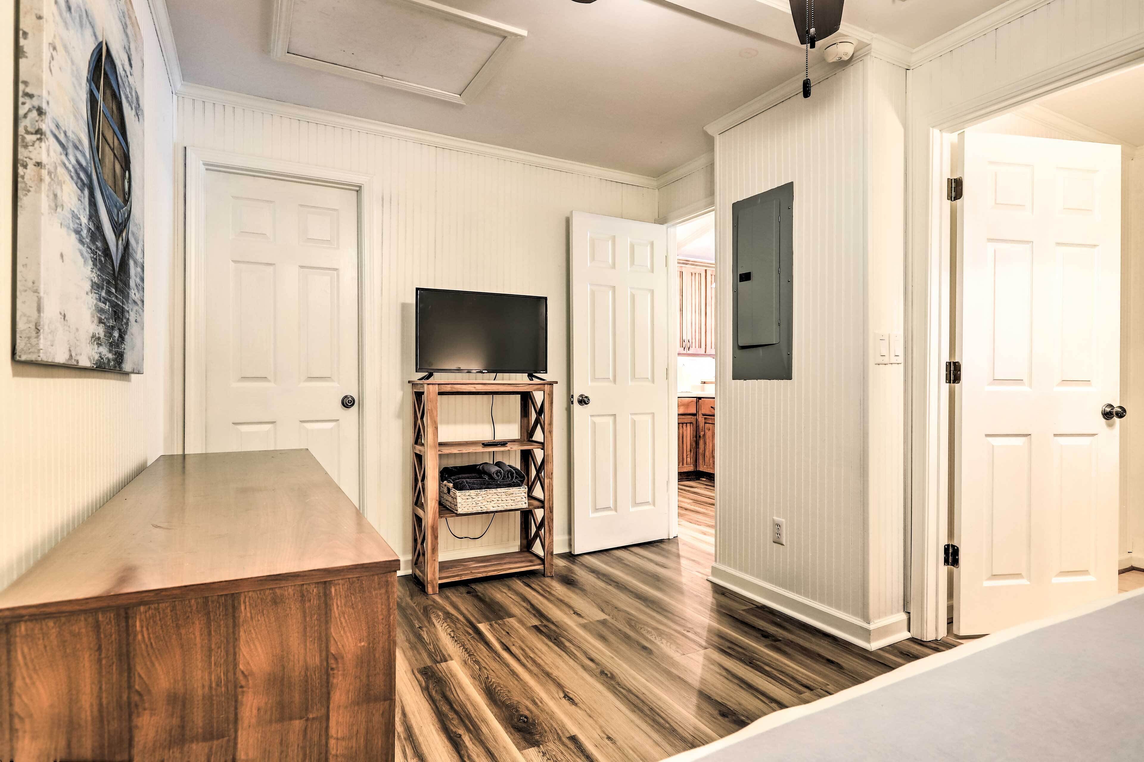 A room with a wooden table, a TV on a wooden stand, and white doors.