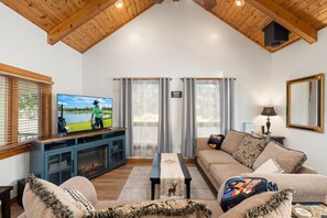 A living room with a television, sofa, and a view of a lake.