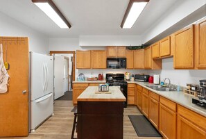 A modern kitchen with wooden cabinets, a central island, a microwave, stove, and a refrigerator.