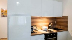 A modern kitchen with white cabinetry, a wooden countertop, a sink, a stove, and a refrigerator. - Le Gatsby - Superbe cocon cosy 1mn place Bellecour (Lyon)