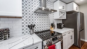 Een moderne keuken met witte kastjes, een roestvrijstalen fornuis en een achterwand met een patroon.