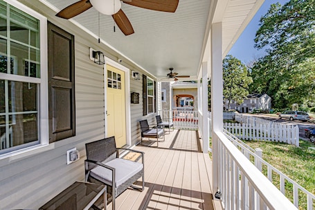 A covered porch with outdoor seating, a ceiling fan, and a view of the neighborhood.