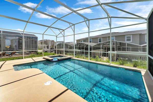 A swimming pool with a glass enclosure, surrounded by houses, and a hot tub. - Champions Gate by CozyKey (Davenport)
