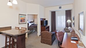 A hotel room with a dining area, a bed, a television, and a desk with a lamp. - 1 Bedroom | Free Breakfast, Pool Access (Oklahoma City)