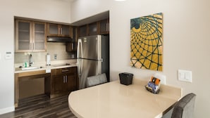 Une cuisine moderne dotée d’un îlot central, d’appareils électroménagers en acier inoxydable et de meubles de rangement en bois.